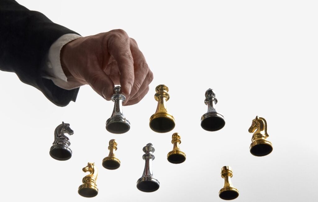 Businessman choosing silver chess piece on white backdrop.