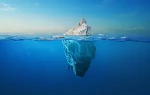 white iceberg floats in the ocean with a view underwater.