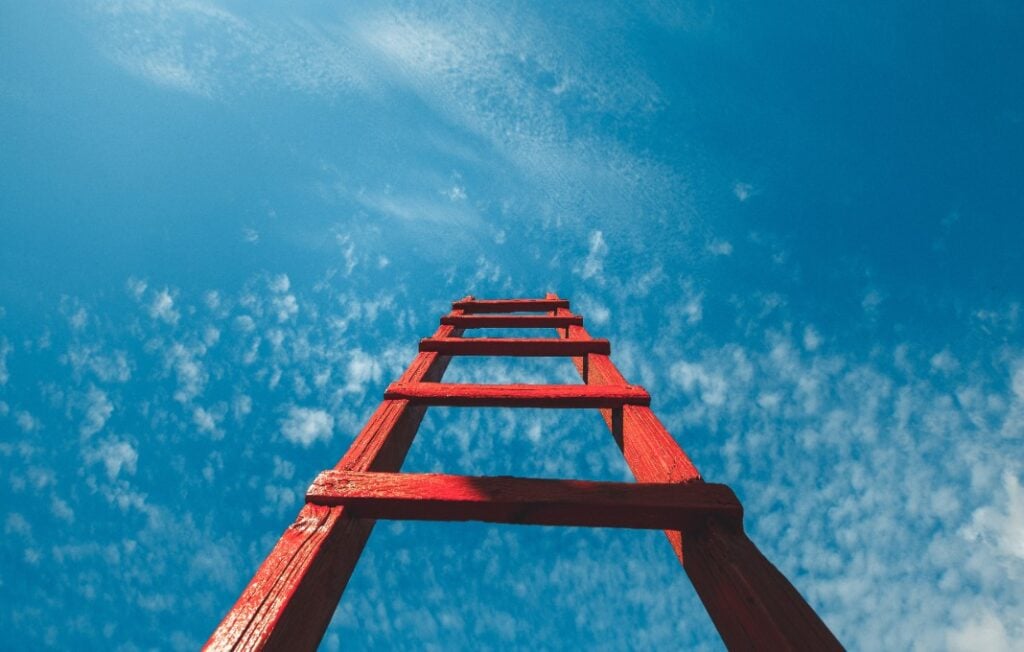 Red Staircase Rests Against Blue Sky, Front View.